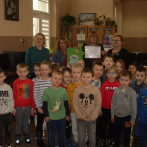 Wnętrze biblioteki. Zdjęcie grupowe dzieci uczestniczących w spotkaniu.