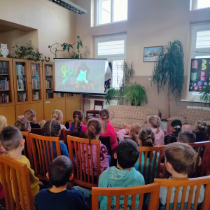 W bibliotece. Grupa dzieci ogląda film. 