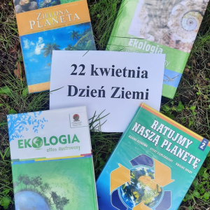  Na trawie płasko okładką do przodu leżą 4 książki o tematyce ekologicznej. Na środku między książkami biała kartka z napisem: 22 kwietnia Dzień Ziemi