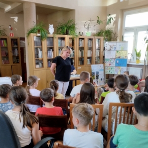 W bibliotece. Dzieci patrzą na kobietę, która prowadzi spotkanie. 