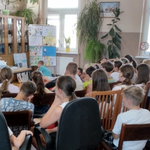 W bibliotece. Dzieci patrzą na kobietę, która prowadzi spotkanie.