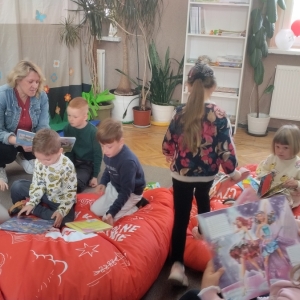 Przedszkolaki spędzają czas w bibliotece. Siedzą na pufach i przeglądają książki. 