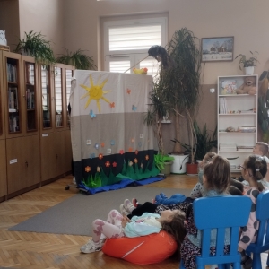 W bibliotece. Grupa dzieci ogląda teatrzyk kukiełkowy.