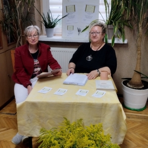 W bibliotece. Dwie kobiety siedzą przy stoliku. 