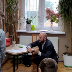 W bibliotece. Prowadzący i dwóch ochotników pokazują eksperyment z kurzym jajkiem.