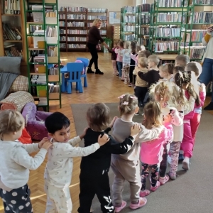 W bibliotece. Grupa dzieci bawi się w pociąg zwiedzający bibliotekę.