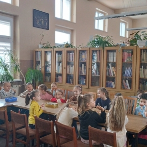 W bibliotece. Dzieci siedzą przy stolikach i wykonują prace plastyczne.