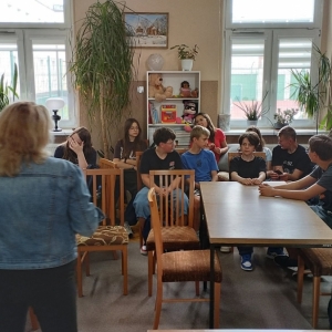 W bibliotece. Grupa dzieci siedzi przy stolikach. 