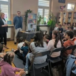 W bibliotece. Grupa osób patrzy na osoby, które prowadzą spotkanie.