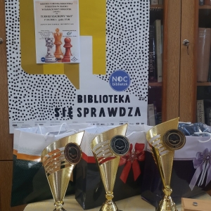 W bibliotece. Na stoliku ustawione puchary.