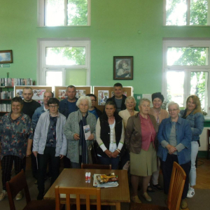 Grupa uczestników spotkania pozuje do wspólnego zdjęcia na tle wykonanych prac.