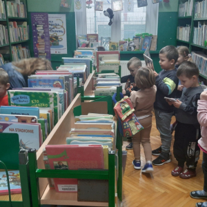 W bibliotece, dział dla dzieci. Grupa dzieci przegląda książki