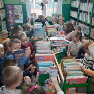 W bibliotece, dział dla dzieci. Grupa dzieci przegląda książki.