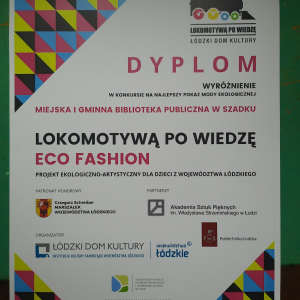 Dyplom. Na białym tle kolorowa grafika. U góry narysowana lokomotywa. W górnym lewym rogu kolorowe trójkąty.