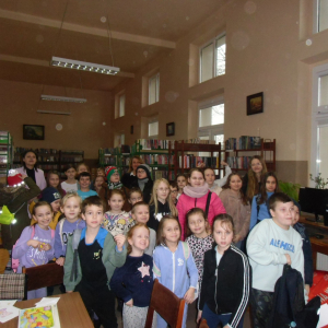 Wnętrze biblioteki. Zdjęcie grupowe dzieci uczestniczących w spotkaniu.