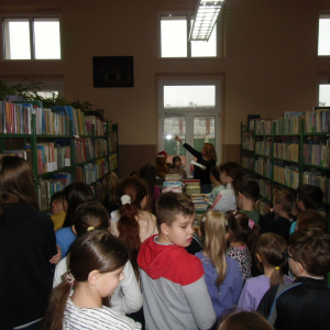 W bibliotece. Grupa dzieci zwiedza bibliotekę i zapoznaje się z ksiegozbiorem biblioteki.