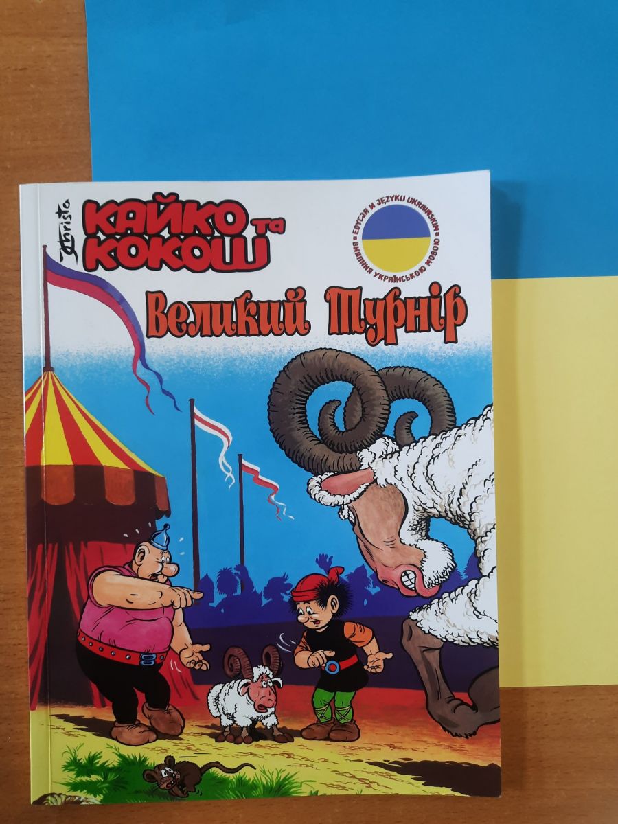 Książka dla dzieci w języku ukraińskim. Leży płasko na stoliku. Na okładce główni bohaterowie książki: Kajko i Kokosz.